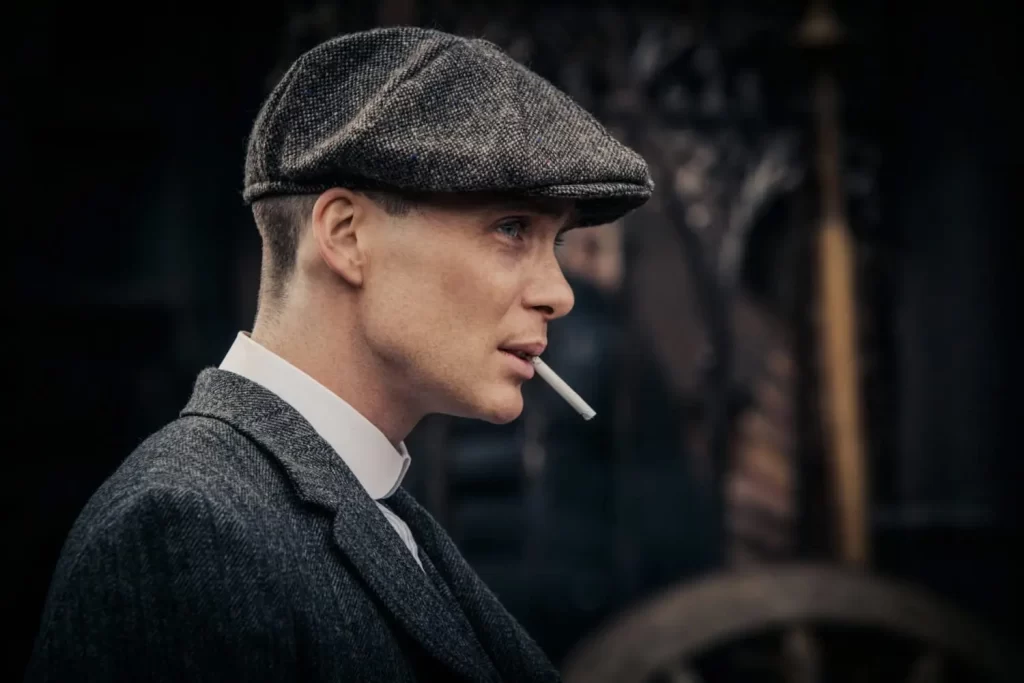 Personagem Thomas Shelby, da série de TV Peaky Blinders, utilizando seu icônico chapéu newsboy. Por causa da série, esse foi um dos tipos de chapéu masculino que mais se destacaram nos últimos anos.