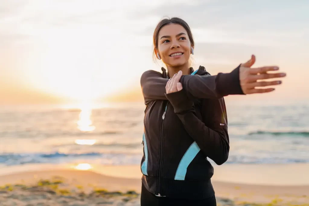 Mulher em uma praia se alongando antes de uma corrida.