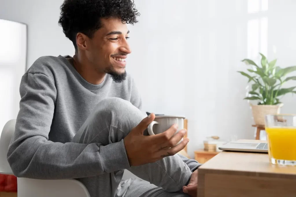 Homem sentado em uma cadeira, tomando café.