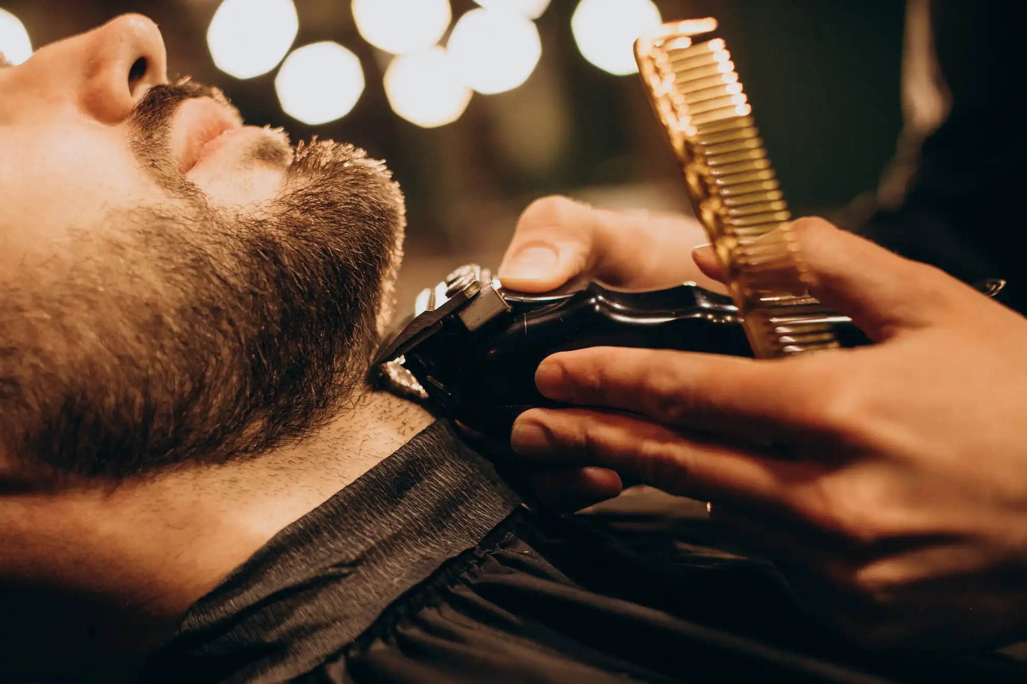 Homem tendo sua barba aparada por um barbeiro.