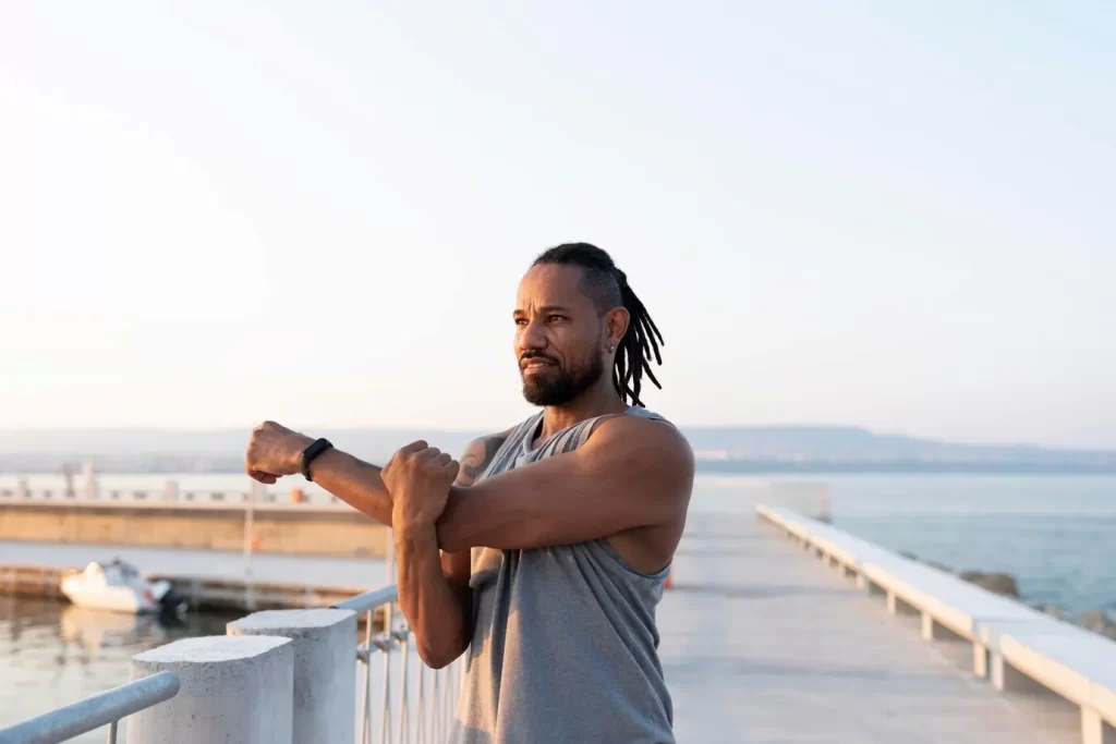 Homem se alongando antes de iniciar os exercícios físicos que fazem parte da sua rotina matinal.