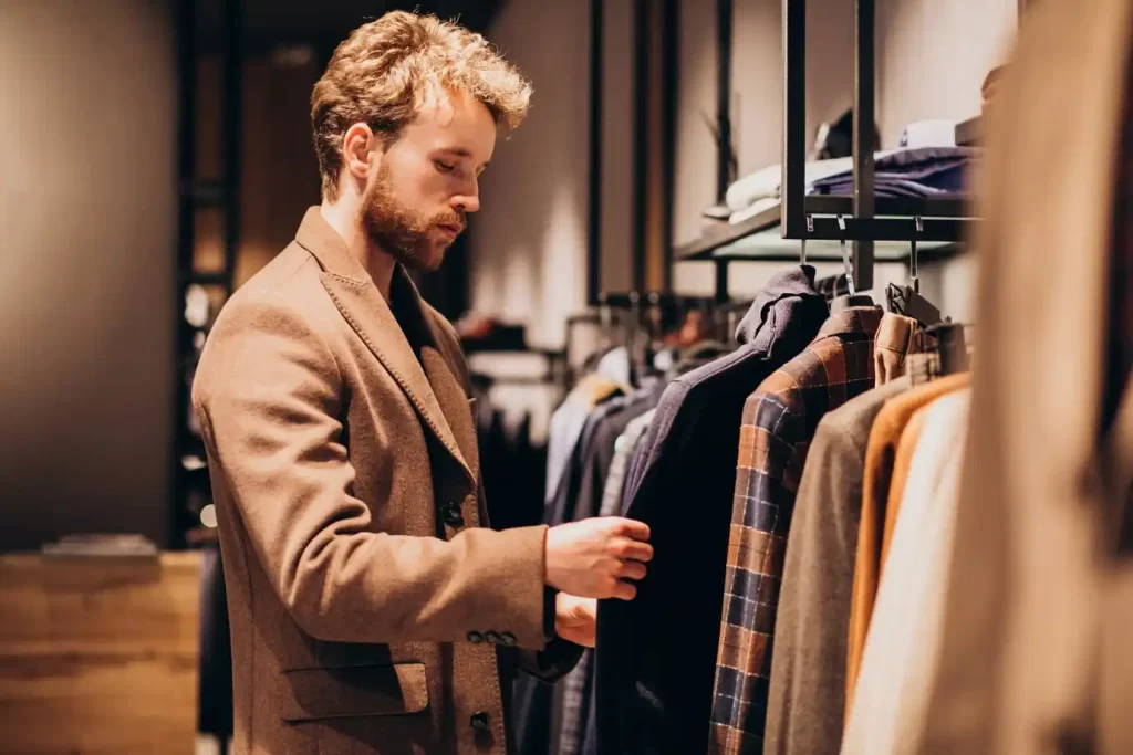 Homem bem-vestido, escolhendo roupas em uma loja.