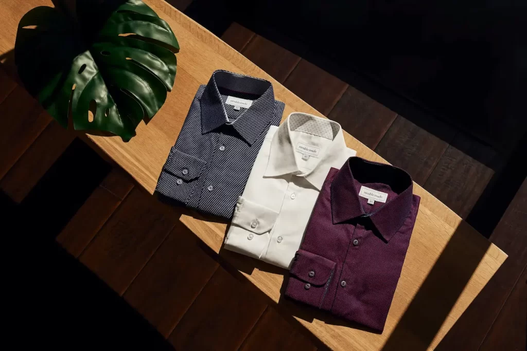 Camisas sociais masculinas sobre uma mesa de madeira.