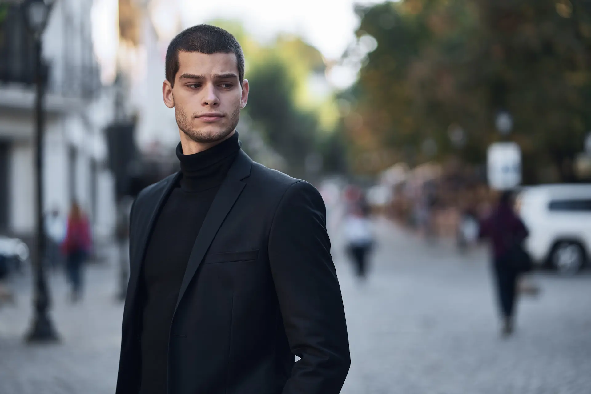 Homem usando um look all black masculino. Na foto, é possível ver que ele usa um blazer sobre uma camiseta de gola alta.