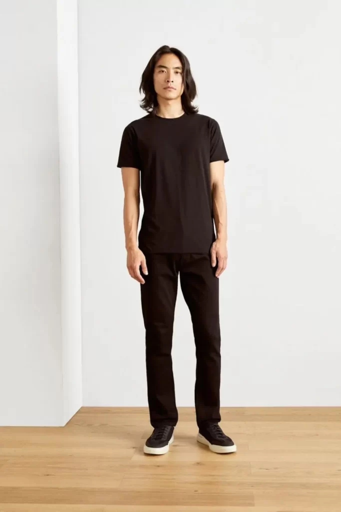 Homem usando um look all black masculino básico, composto por: tênis casual, calça jeans e camiseta.