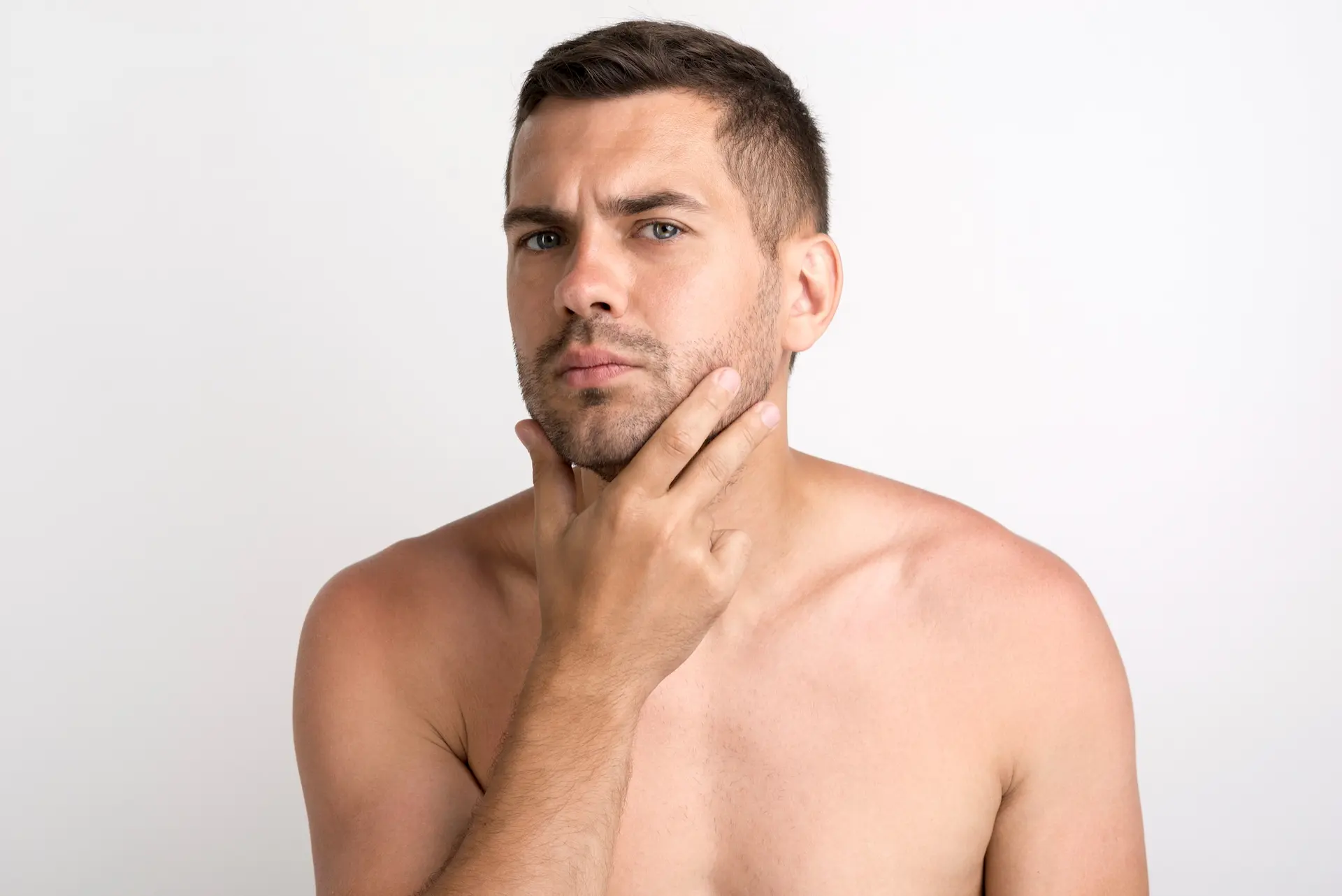 Homem tocando a própria barba, como se a estivesse analisando.