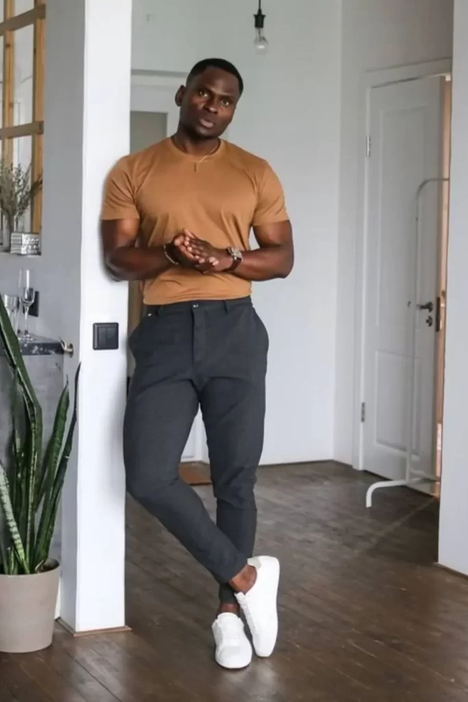 Homem usando camiseta bege, calça cinza e tênis branco.