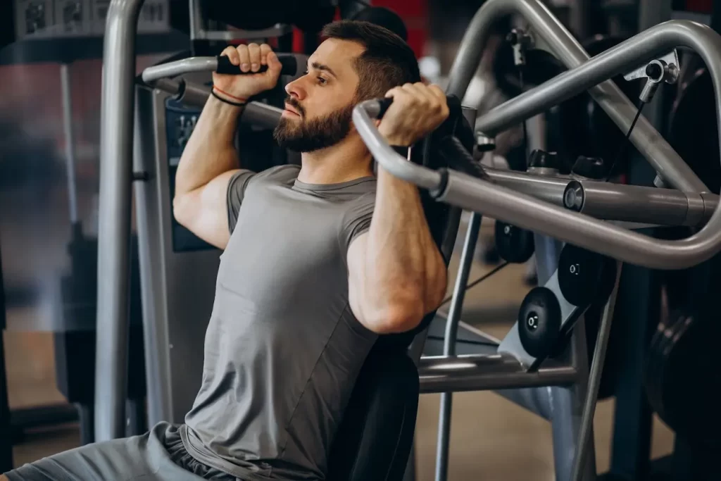 Homem fazendo musculação em um equipamento.