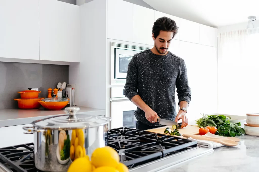 Homem cozinhando. Uma alimentação balanceada é fundamental para um glow up masculino eficaz e duradouro.