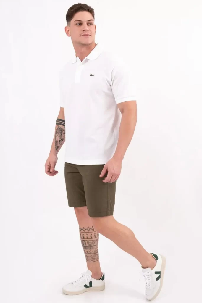 Homem usando camisa polo em look básico, com bermuda e tênis branco.