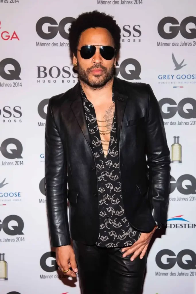 Cantor e ator Lenny Kravitz usando calça de couro, camisa e jaqueta de douro.