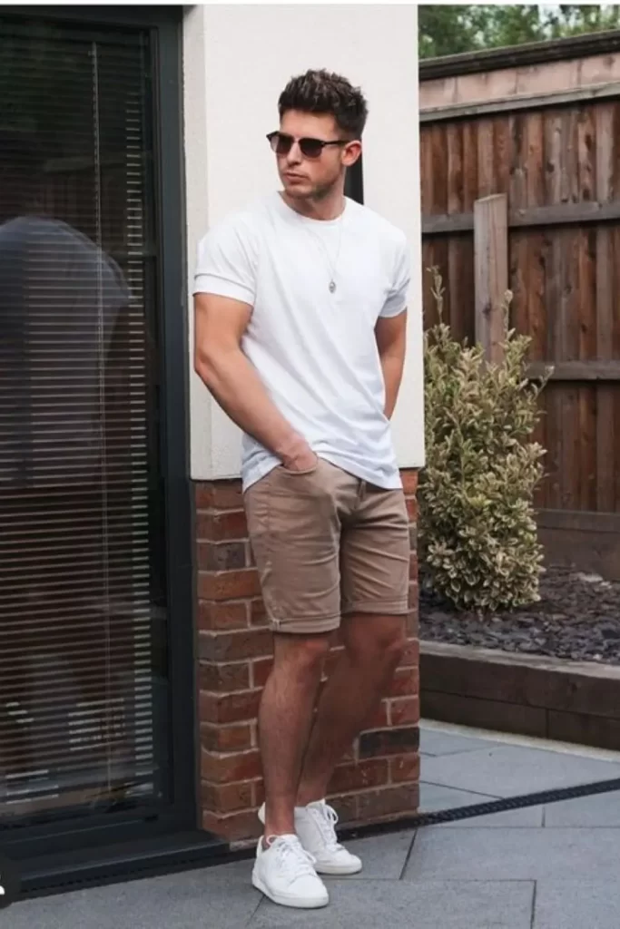 Homem usando camiseta branca, bermuda bege, tênis branco e óculos de sol.