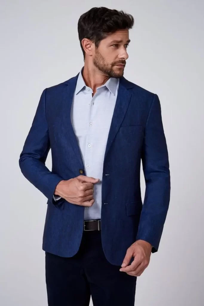 Homem vestido no estilo elegante. Ele usa blazer, camisa social e calça de alfaiataria.