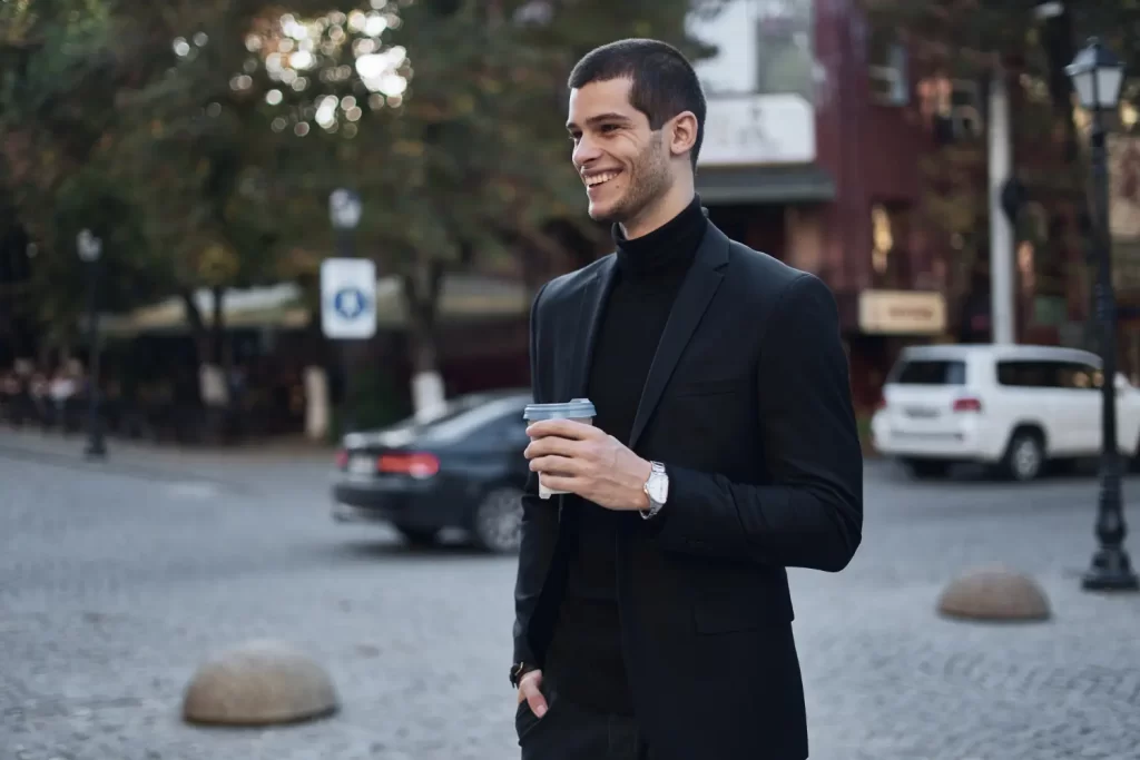 Homem elegante usando calça de alfaiataria, camiseta de gola alta e blazer.