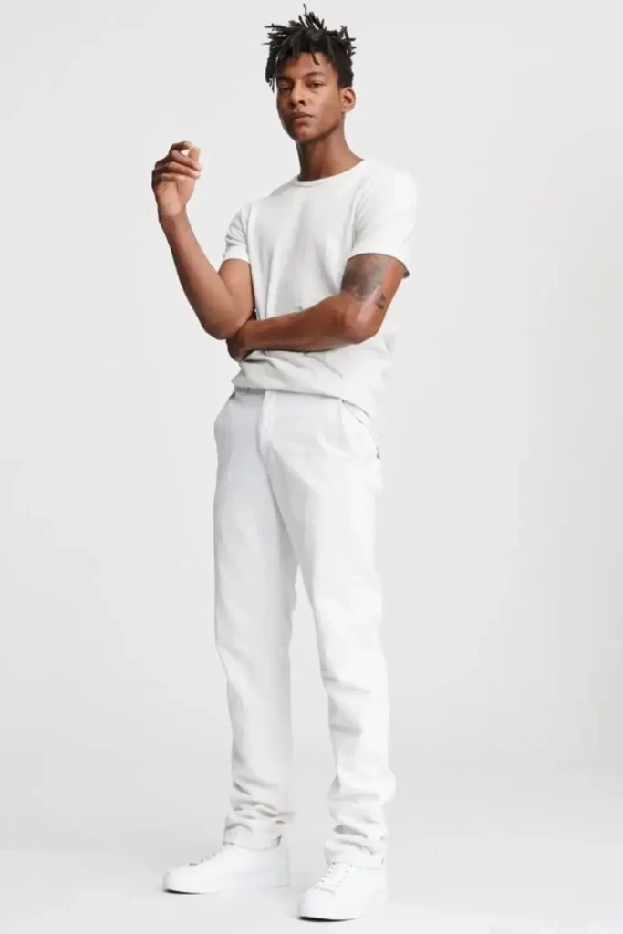 Homem usando camiseta, calça jeans e tênis, tudo na cor branca.