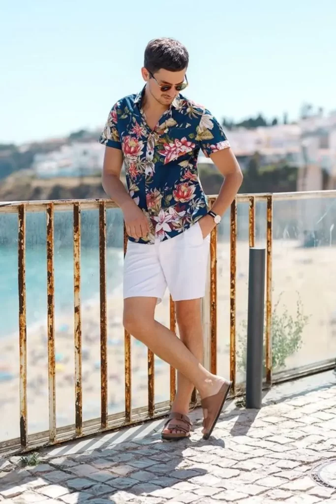 Homem usando camisa floral, bermuda e sandália.