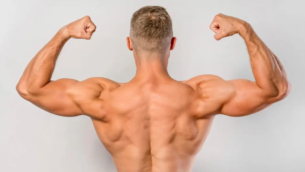 Homem musculoso, de costas, fazendo pose, com os braços levantados e dobrados, contraindo os bíceps.