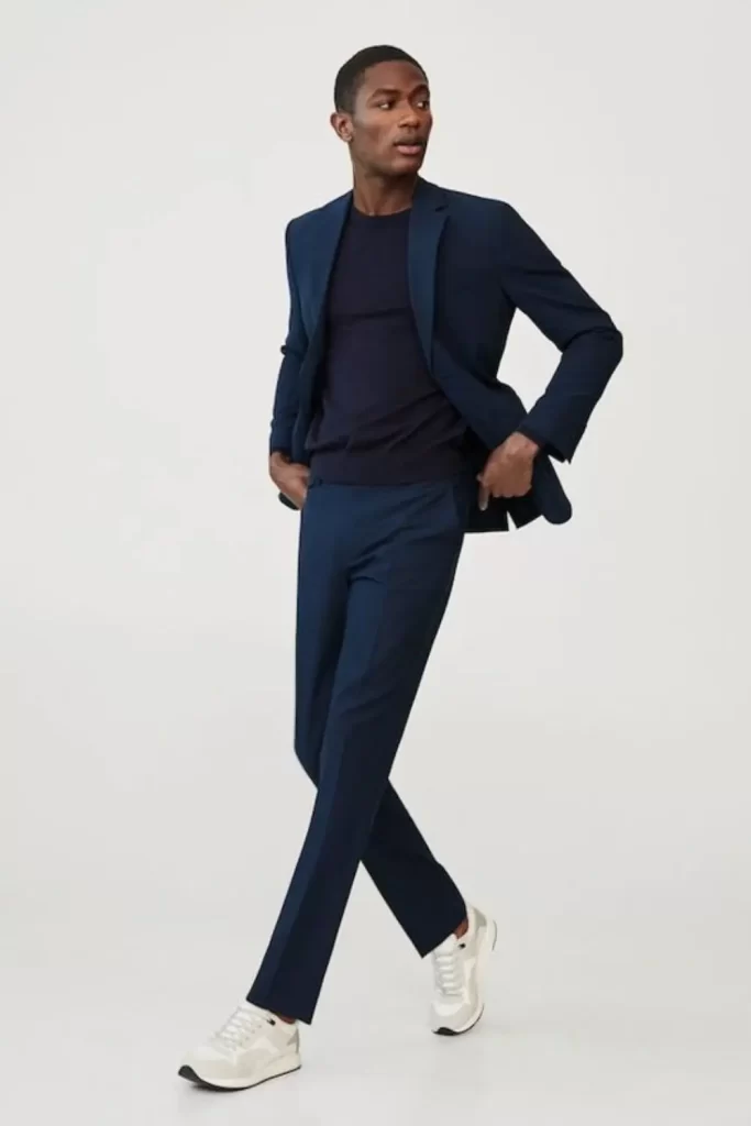 Homem usando calça chino, camiseta, blazer e tênis.
