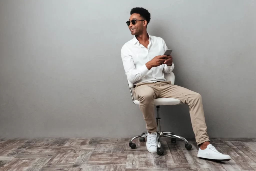 Homem usando calça chino bege, camisa social e tênis brancos.