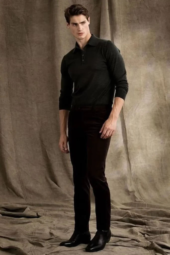 Homem usando calça, bota de couro e camisa de manga longa. Todas as peças na cor preta.