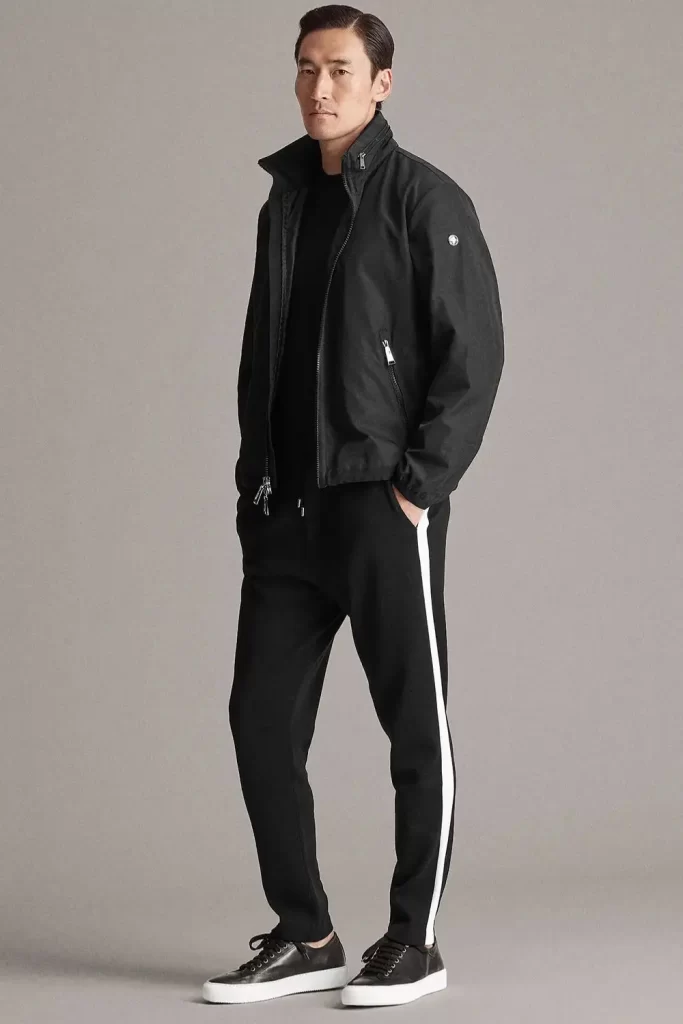 Homem de 40 anos usando tênis, calça jogger, camiseta e jaqueta bomber.