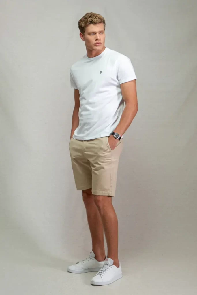 Homem usando camiseta básica, bermuda e tênis casual.