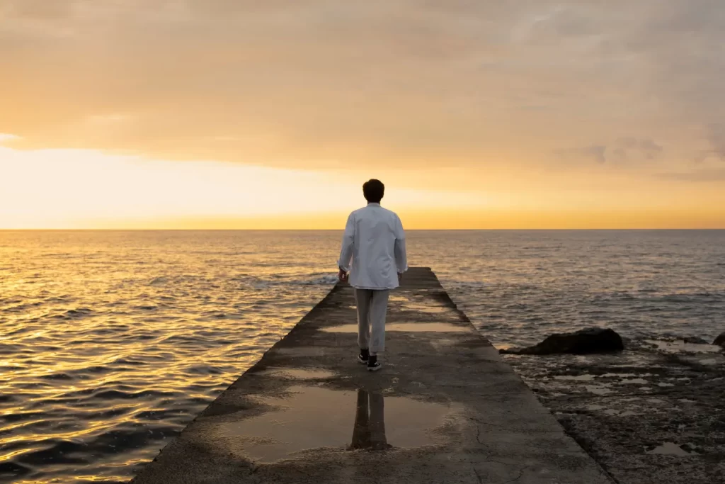 Homem em um píer observando o mar.