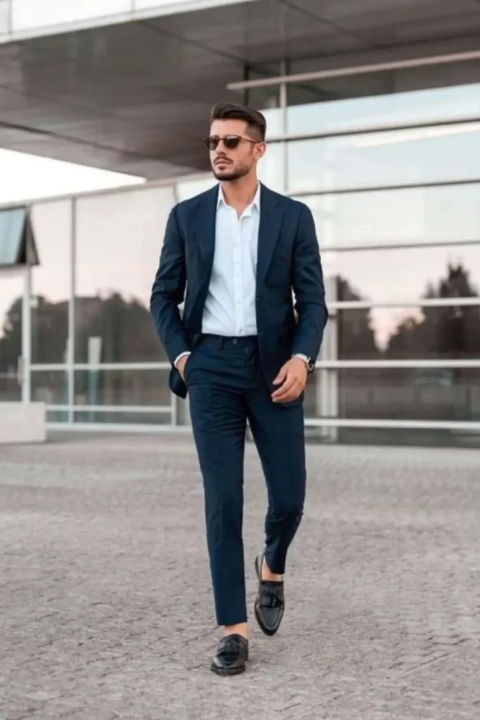Homem usando traje esporte fino com blazer e óculos de sol.