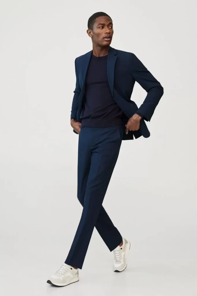 Homem usando blazer, calça de alfaiataria, camiseta básica e tênis casual branco.