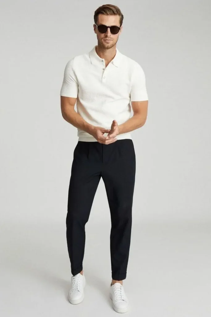Homem usando tênis branco, calça chino, camisa polo e óculos de sol.